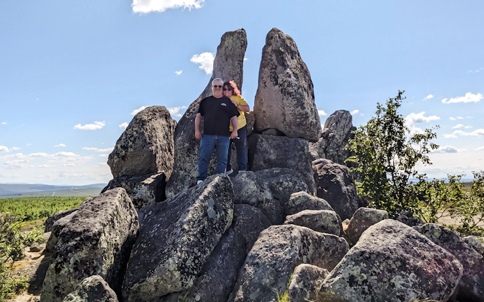 Tourists standing among large rock formations under a clear sky on the Arctic Circle tour.