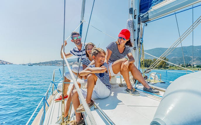 Family enjoying a Barcelona cruise on a sailboat with coastal views.