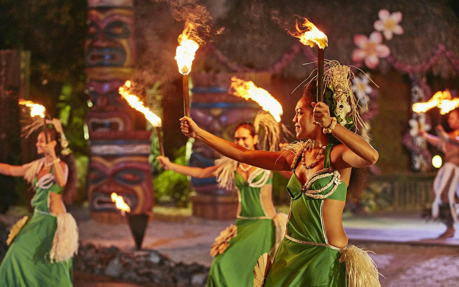 Performers in traditional Polynesian attire dance with fire at PortAventura's Noches de Fuego en Tahití.