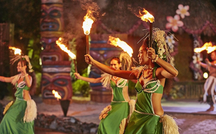 Performers in traditional Polynesian attire dance with fire at PortAventura's Noches de Fuego en Tahití.