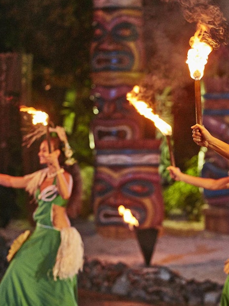 Performers in traditional Polynesian attire dance with fire at PortAventura's Noches de Fuego en Tahití.