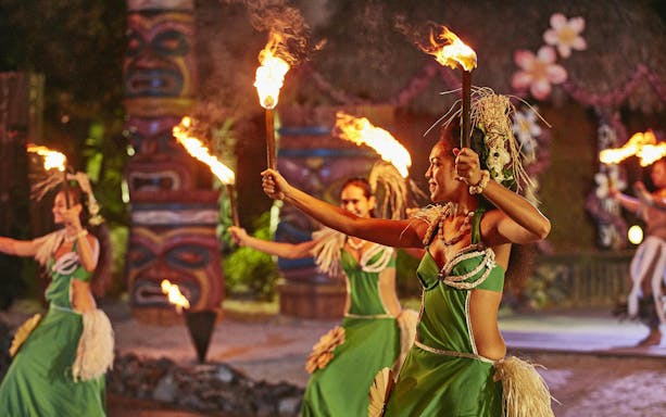 Performers in traditional Polynesian attire dance with fire at PortAventura's Noches de Fuego en Tahití.