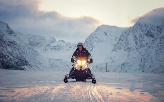 Guest riding a snowmobile in the snowy Lyngen Alps, Tromsø.