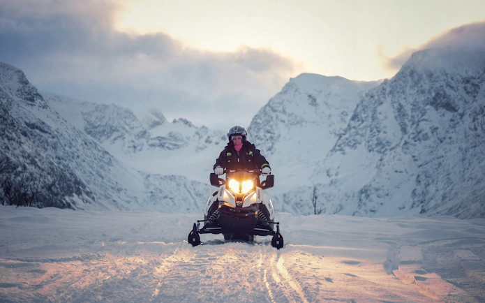 Guest riding a snowmobile in the snowy Lyngen Alps, Tromsø.