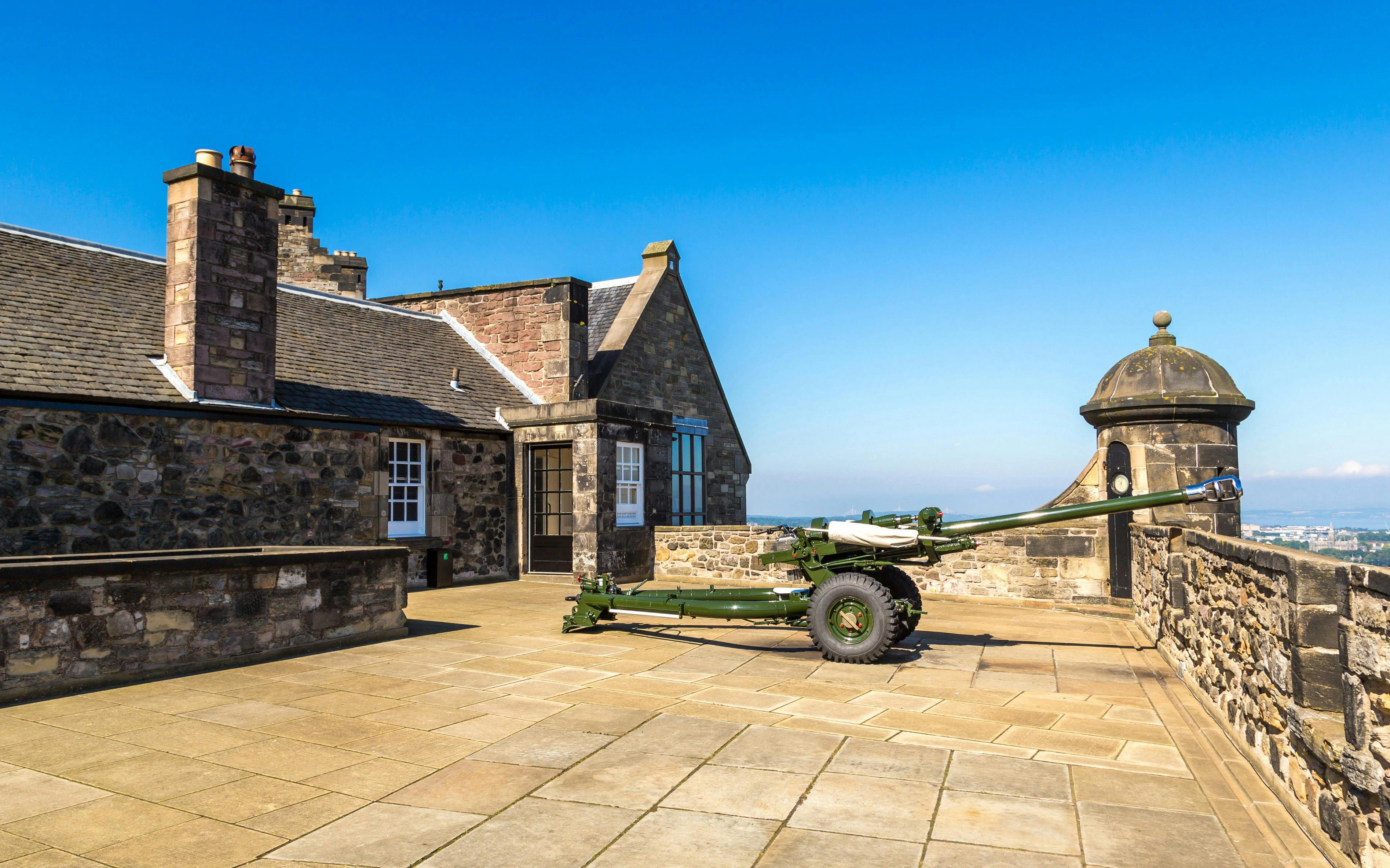 Edinburgh Castle's One O’Clock Gun on the stone terrace with city view.