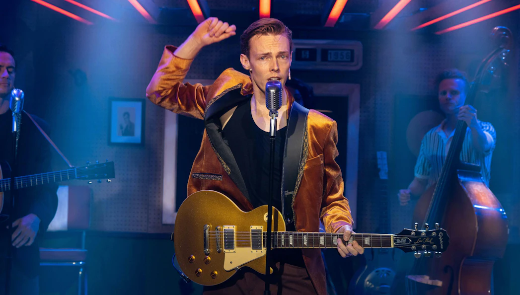 Performer playing guitar on stage during Million Dollar Quartet show.