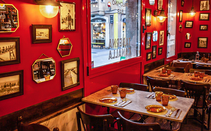 Cozy restaurant interior in La Barceloneta with red walls and framed photos, part of a 3-hour guided food tour.