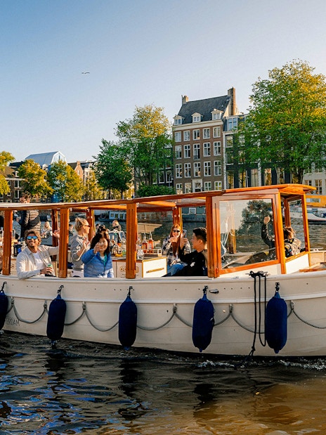 Luxury canal cruise boat with passengers on Amsterdam canal.
