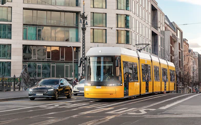 Yellow tram traveling through Berlin city street with modern buildings.