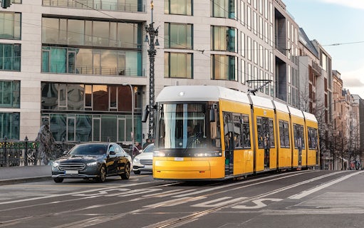 Yellow tram traveling through Berlin city street with modern buildings.