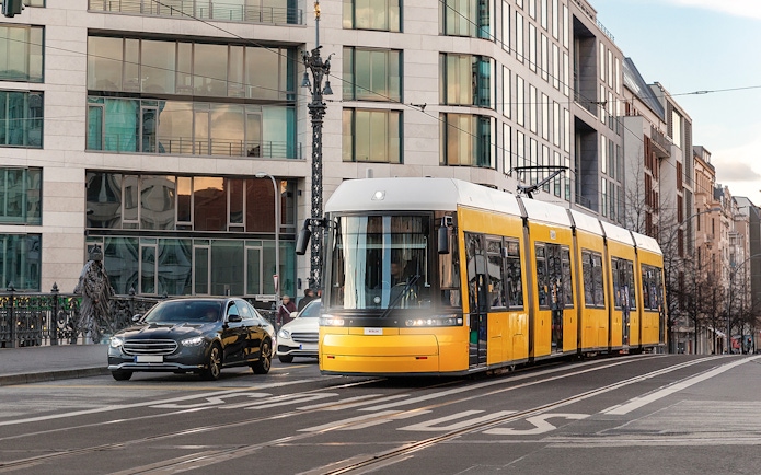 Yellow tram traveling through Berlin city street with modern buildings.