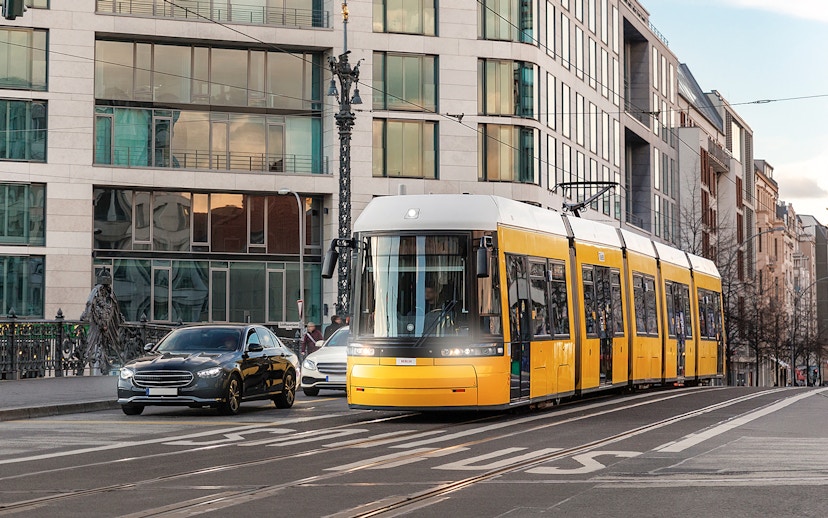 Yellow tram traveling through Berlin city street with modern buildings.