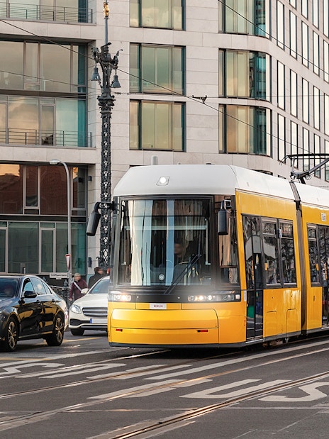 Yellow tram traveling through Berlin city street with modern buildings.