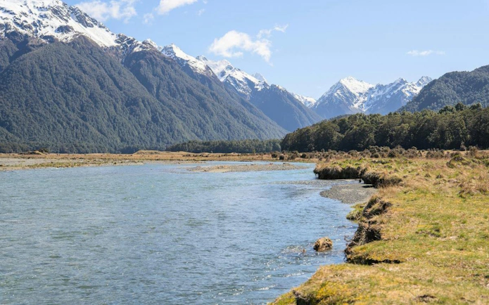 Milford Sound landscape with river, mountains, and forest, viewed from Te Anau departure.