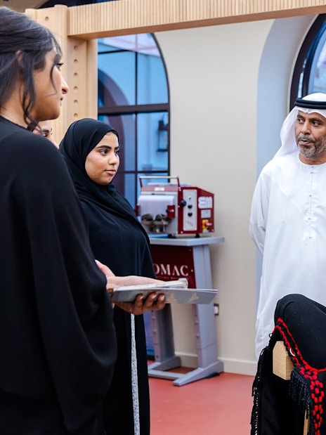 Guide explaining equestrian equipment to visitors at Abu Dhabi Royal Equestrian Arts tour.