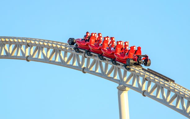 Roller coaster at Ferrari World Abu Dhabi with riders in red cars.