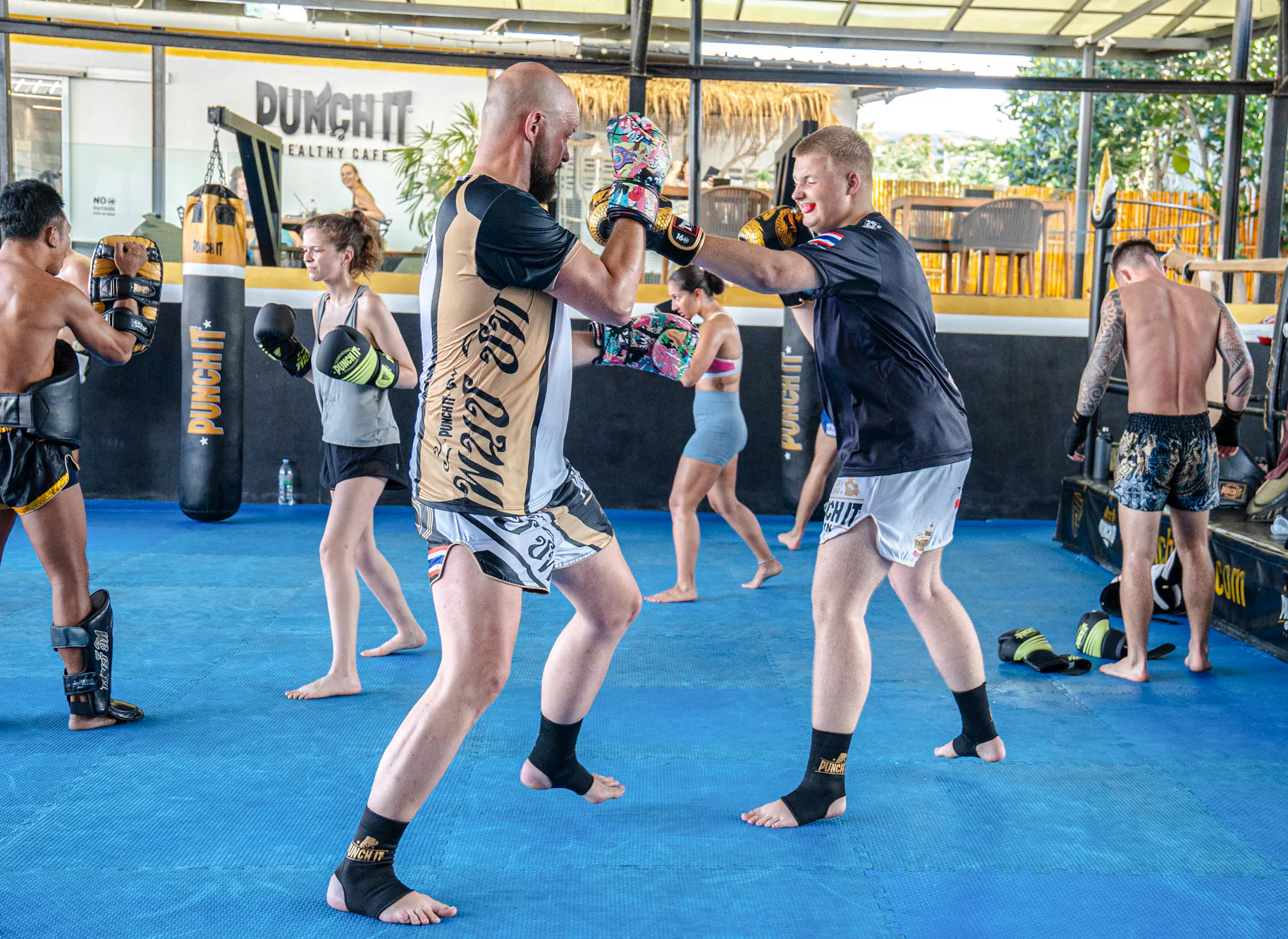 Beginners practicing Muay Thai boxing techniques in a Koh Samui training class.