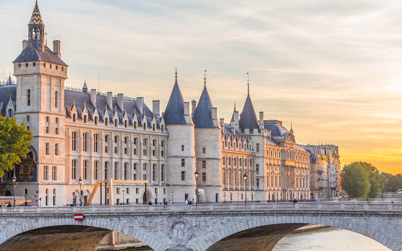 Conciergerie and Seine River at sunset in Paris.
