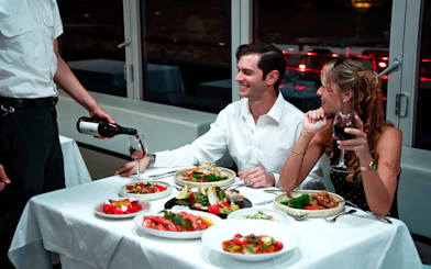 Waiter serving wine to couple on Glass Boat Dinner Cruise in Sydney.