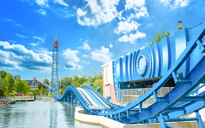 AQUAMAN™ Power Wave roller coaster at Six Flags Over Texas with water track and blue sky.