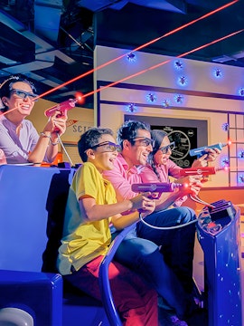 Family enjoying a laser tag ride at an indoor amusement park.