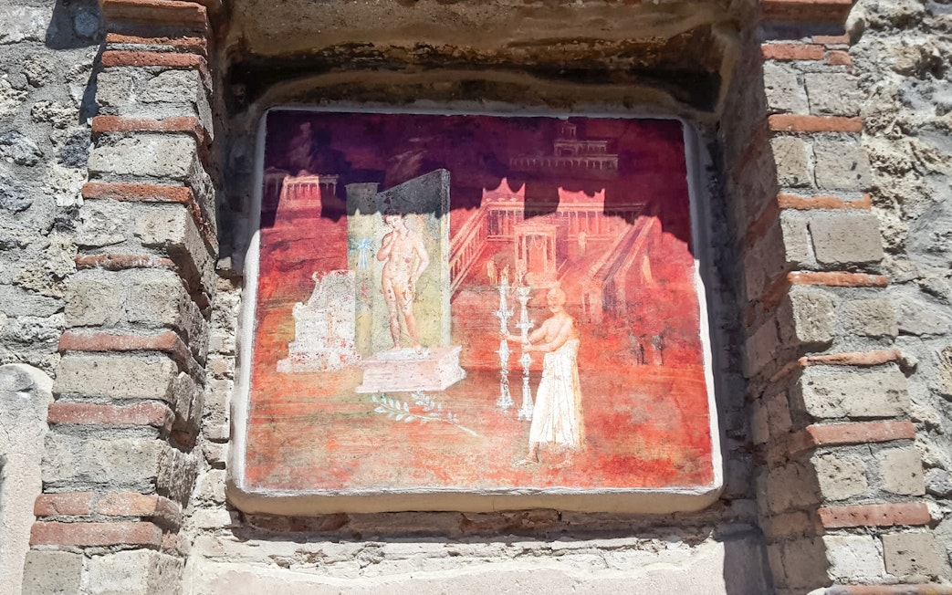 Ancient fresco in Pompeii depicting a figure near a columned structure.