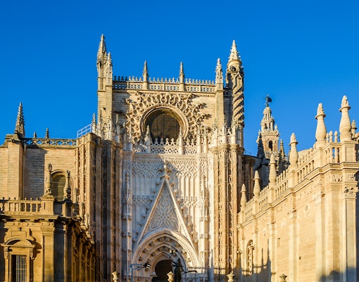 Seville Cathedral exterior with Gothic architecture and Giralda tower in Seville, Spain.