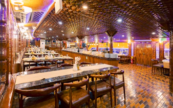 Interior dining area of Alexandra VIP Dhow Cruise with set tables and ornate wooden decor.