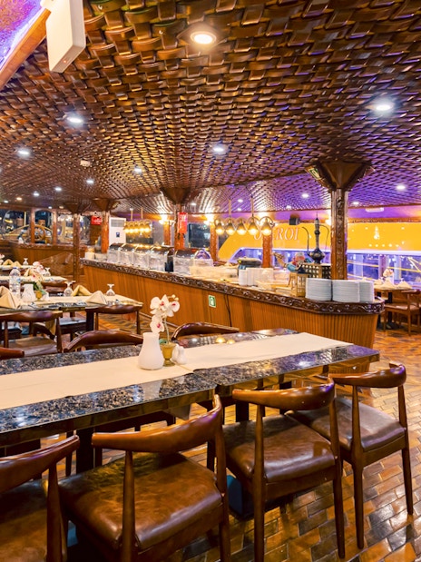 Interior dining area of Alexandra VIP Dhow Cruise with set tables and ornate wooden decor.