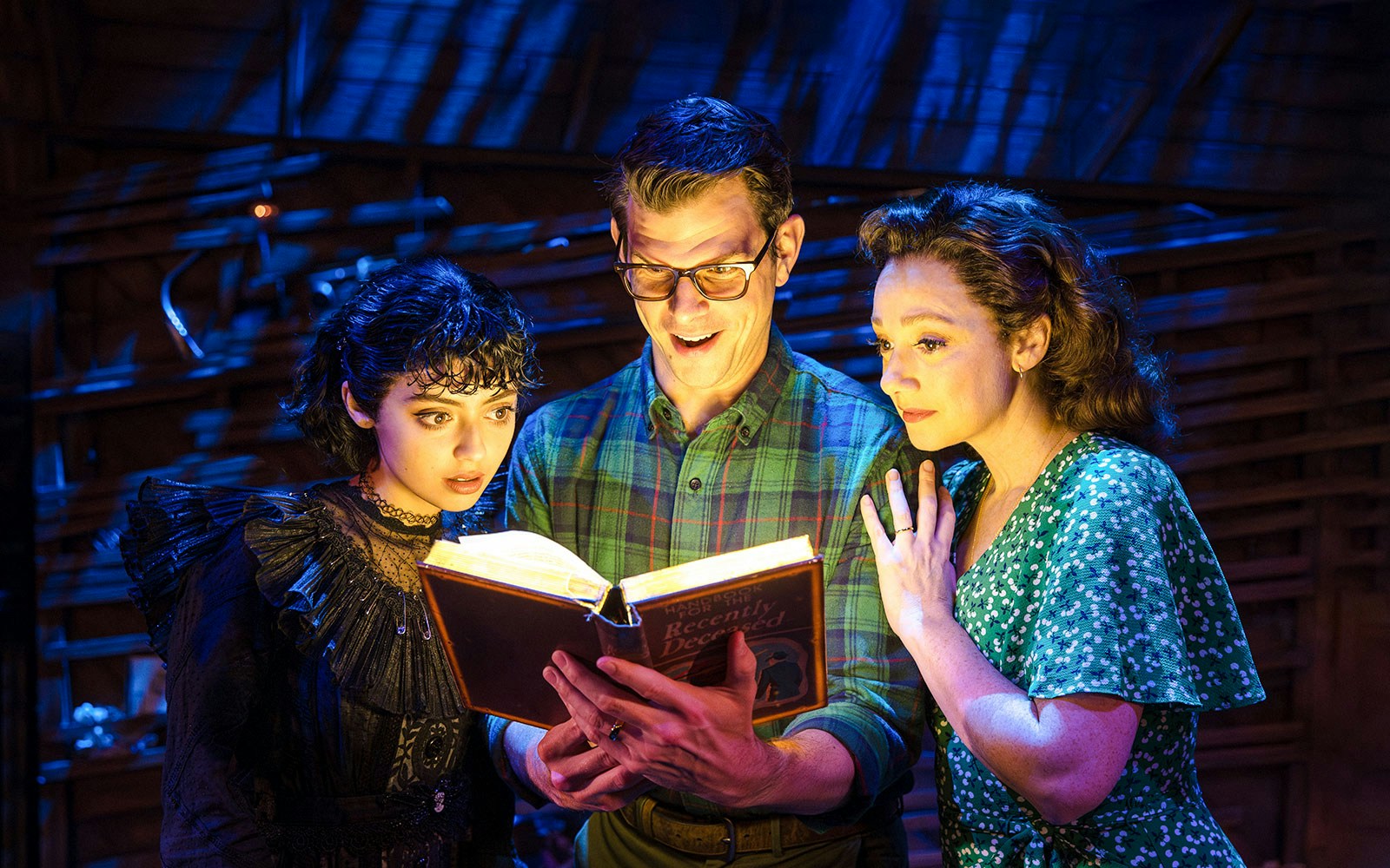 Actors reading glowing book on stage at Beetlejuice Broadway show.
