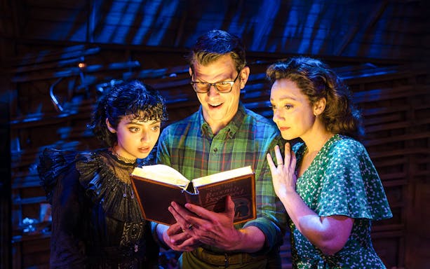 Actors reading glowing book on stage at Beetlejuice Broadway show.