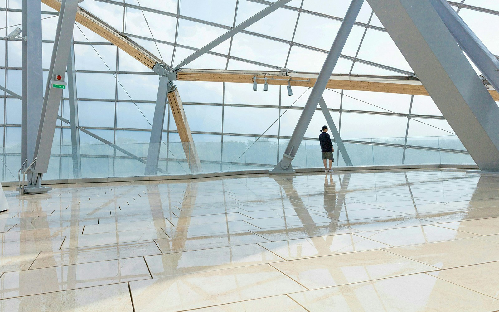 Visitor near glass window at Fondation Louis Vuitton, Paris.