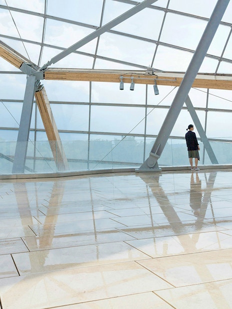 Visitor near glass window at Fondation Louis Vuitton, Paris.