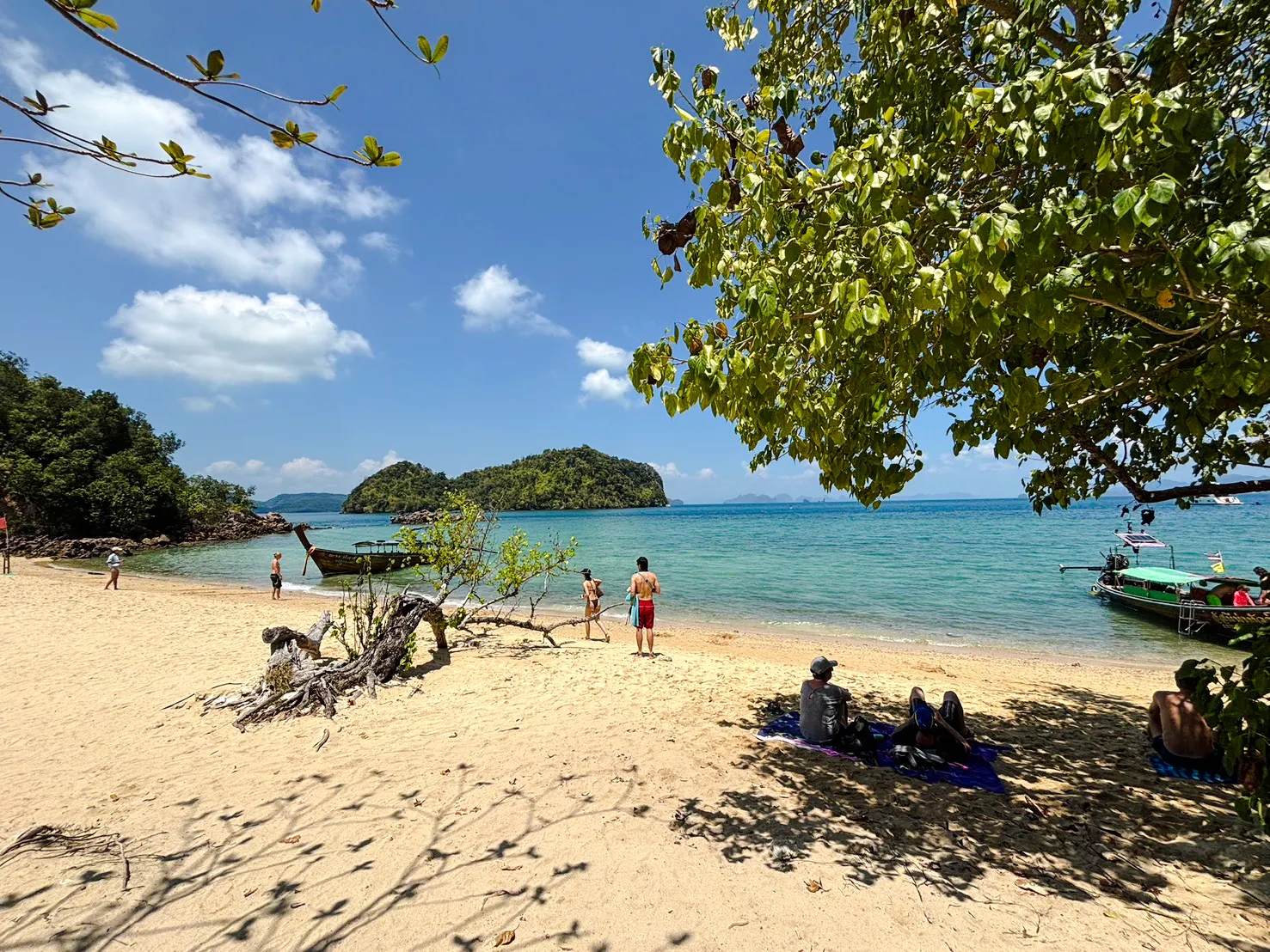 Longtail boat on Hong Island beach with tourists relaxing and snorkeling, Krabi.