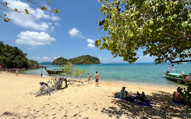 Longtail boat on Hong Island beach with tourists relaxing and snorkeling, Krabi.
