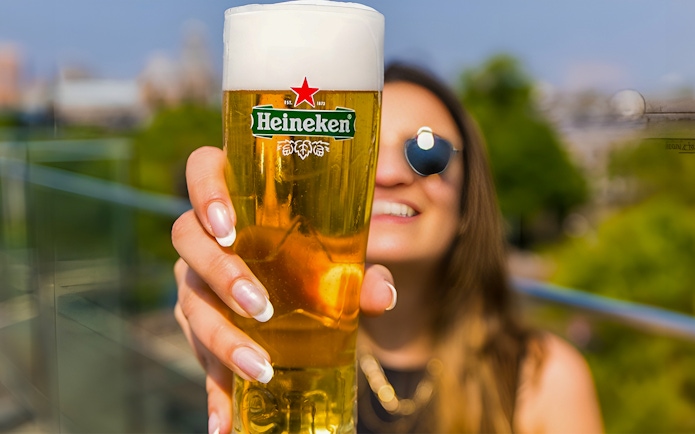 Heineken Experience guest holding a beer glass in Amsterdam.