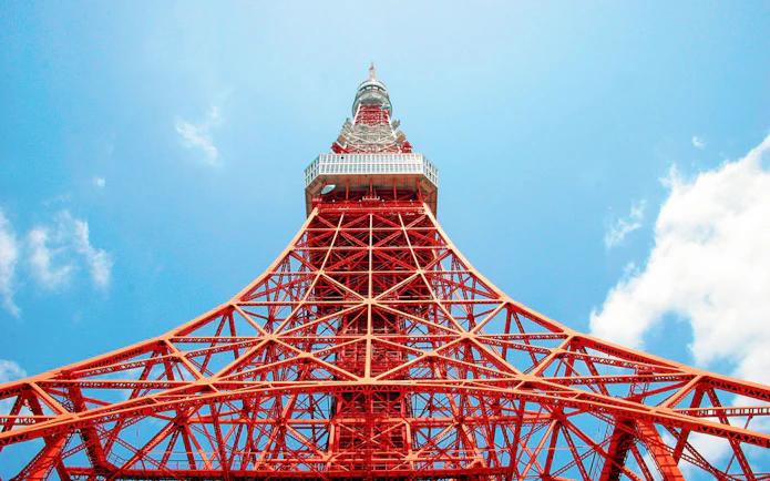 Tokyo Tower's red lattice structure against a blue sky in Tokyo, Japan.