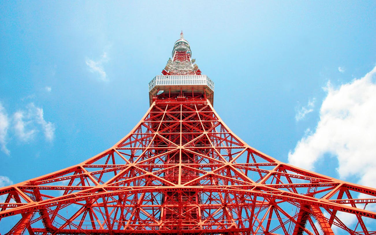 Tokyo Tower's red lattice structure against a blue sky in Tokyo, Japan.