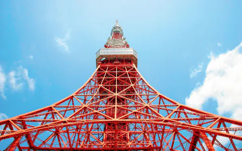 Tokyo Tower's red lattice structure against a blue sky in Tokyo, Japan.