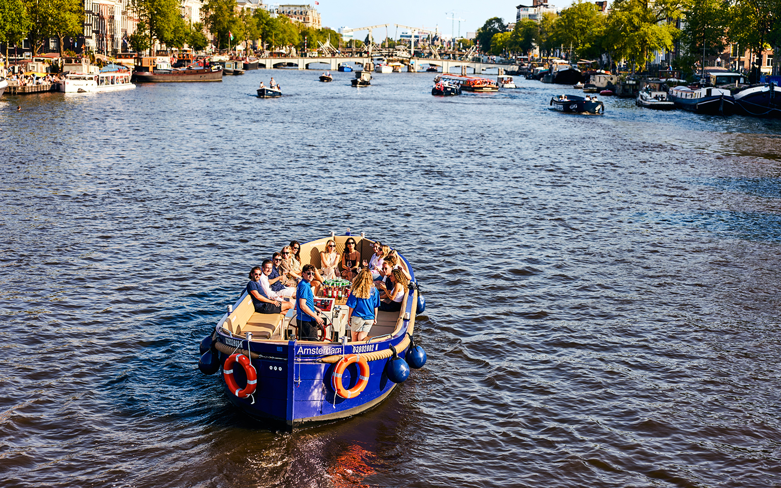 Tourists enjoying a canal cruise in Amsterdam with cityscape views.