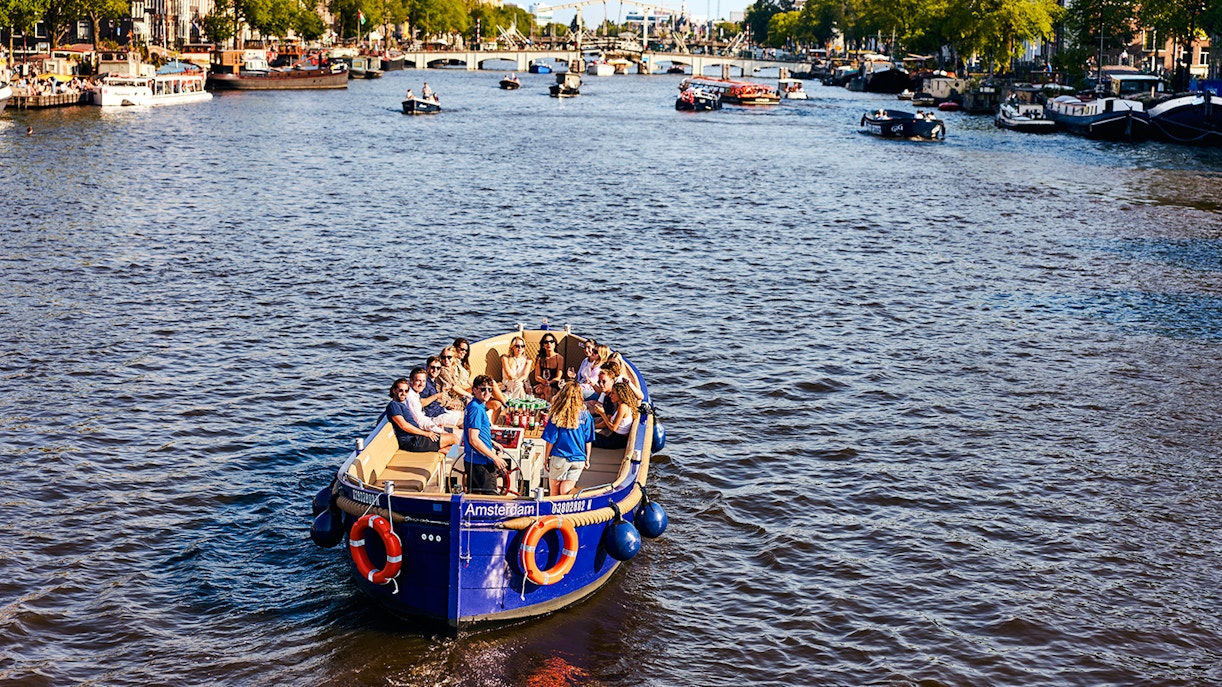 Tourists enjoying a canal cruise in Amsterdam with cityscape views.