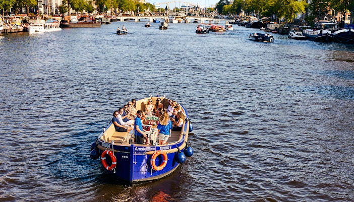 Tourists enjoying a canal cruise in Amsterdam with cityscape views.