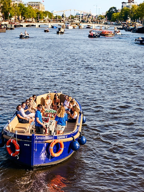 Tourists enjoying a canal cruise in Amsterdam with cityscape views.