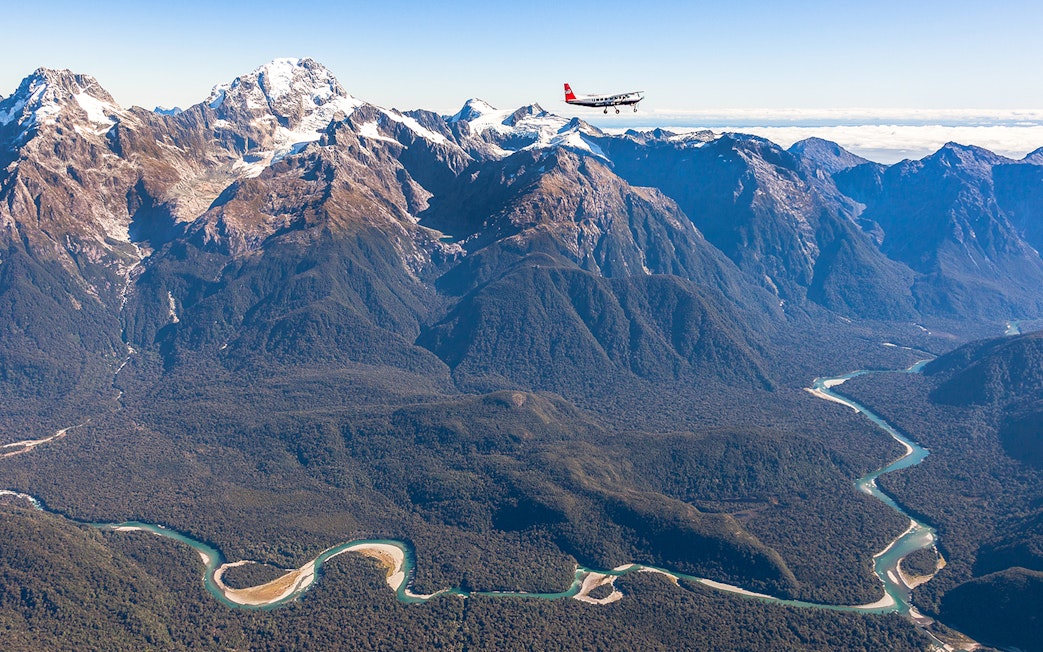 Aerial view of Milford Sound mountains with a plane flying over, showcasing scenic flyover from Queenstown.