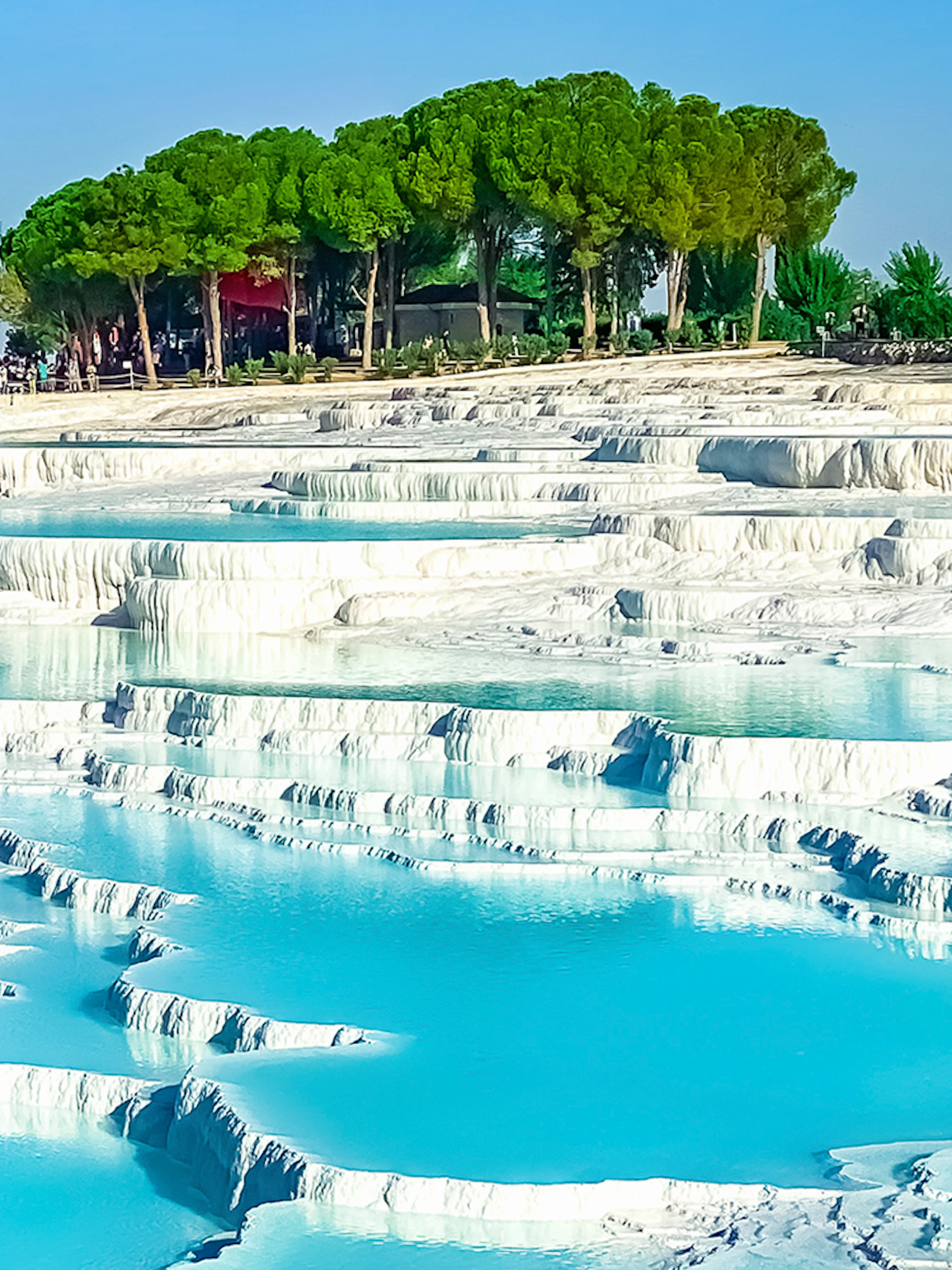Terraced thermal pools of Pamukkale with tourists exploring the site in Turkey.