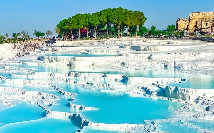Terraced thermal pools of Pamukkale with tourists exploring the site in Turkey.