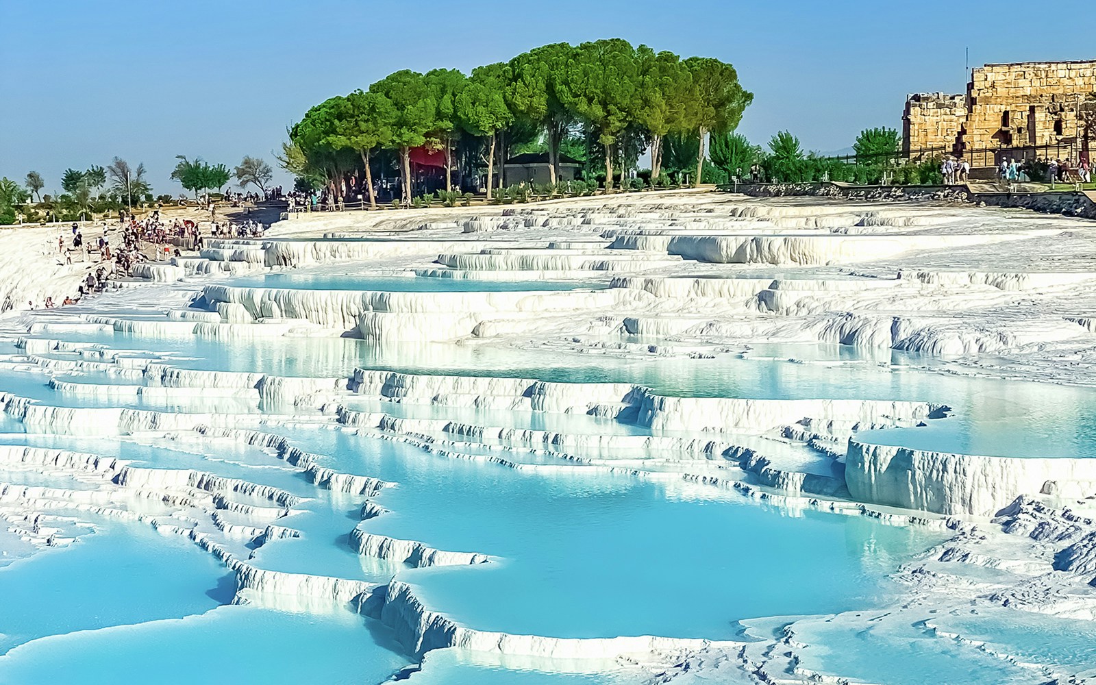 Terraced thermal pools of Pamukkale with tourists exploring the site in Turkey.