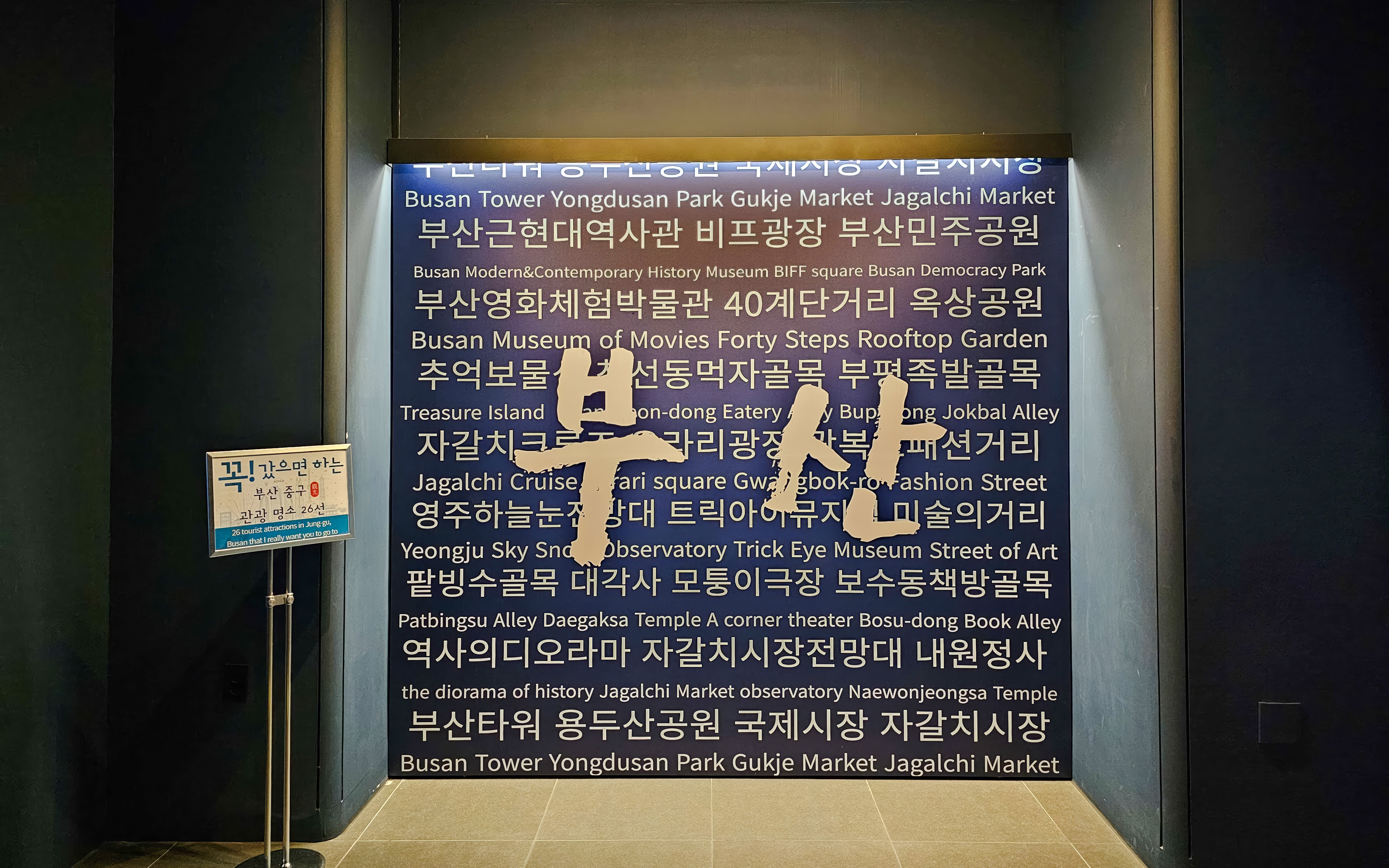 Busan Tower interior wall with tourist attractions listed in Korean and English.
