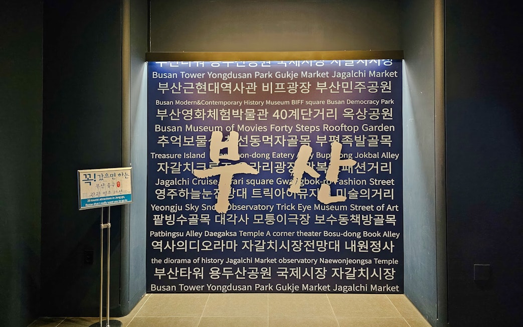 Busan Tower interior wall with tourist attractions listed in Korean and English.