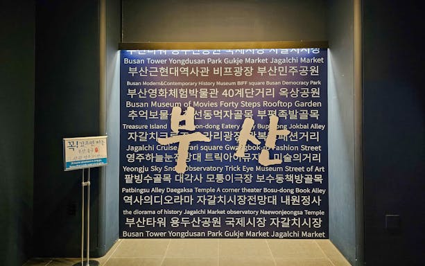 Busan Tower interior wall with tourist attractions listed in Korean and English.